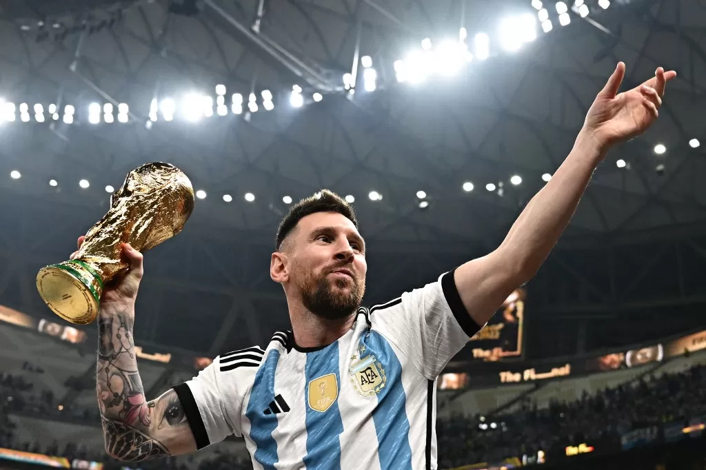 Lionel Messi saat mengangkat trofi Piala Dunia 2022. Striker Paris Saint-Germain itu dikabarkan bakal tampil menghadapi timnas Indonesia di FIFA matchday bulan depan. (Anne-Christine POUJOULAT / AFP)