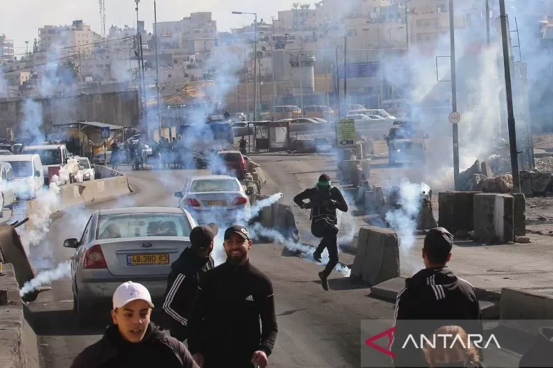Foto arsip: Pengunjuk rasa Palestina berlarian untuk berlindung dari tabung gas air mata yang ditembakkan pasukan keamanan Israel dalam bentrokan di pos pemeriksaan Qalandia di dekat Kota Ramallah.