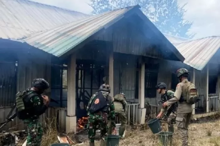 Personel TNI-Polri berupaya memadamkan perumahan petugas kesehatan yang dibakar KKB di Ilaga, Kabupaten Puncak, Papua Tengah, Senin (11/9). (Antara)