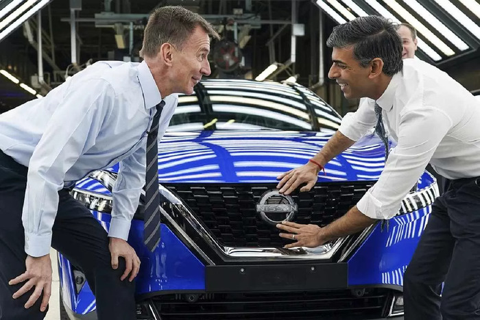 Perdana Menteri Inggris Rishi Sunak (kanan) dan Menteri Keuangan Jeremy Hunt menempelkan lencana Nissan pada mobil saat mereka mengunjungi produsen mobil Nissan, di Sunderland, Inggris, Jumat (24/11).