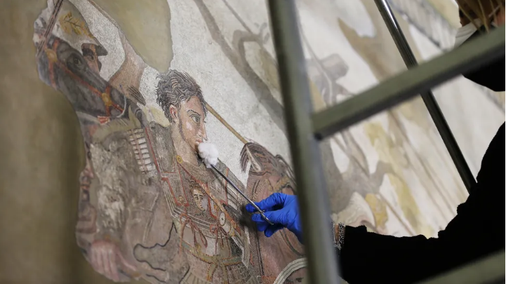 Seorang pemulih mengerjakan mosaik Alexander Agung pada tahun 2021. Mosaik ini berasal dari Pompeii dan kini dipamerkan di Museum Arkeologi Nasional Napoli.