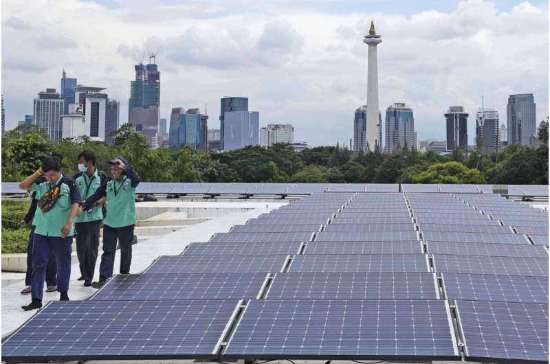 Pekerja berjalan di dekat panel surya yang menyediakan sebagian daya listrik ke Masjid Istiqlal dengan latar belakang cakrawala kota, di Jakarta, Indonesia, Rabu, 29 Maret 2023.