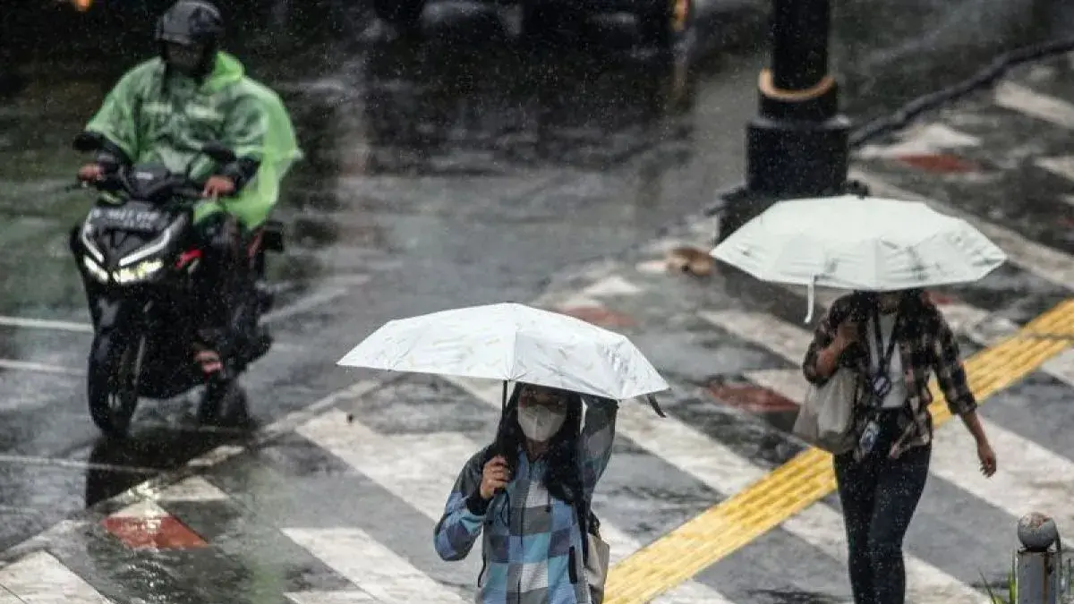 Warga berjalan dengan menggunakan payung saat hujan di Depok, Jawa Barat.