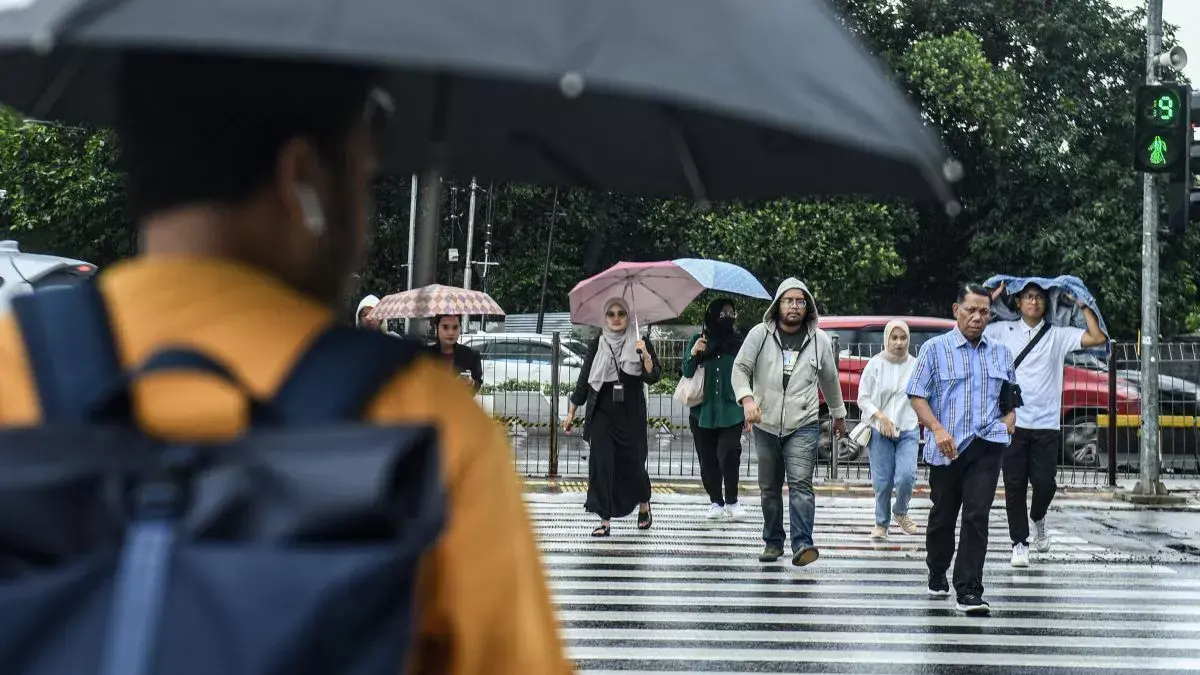 Sejumlah warga menyeberang jalan saat hujan di Jakarta, Jumat (15/3/2024) (Muhammad Adimaja/ANTARA)