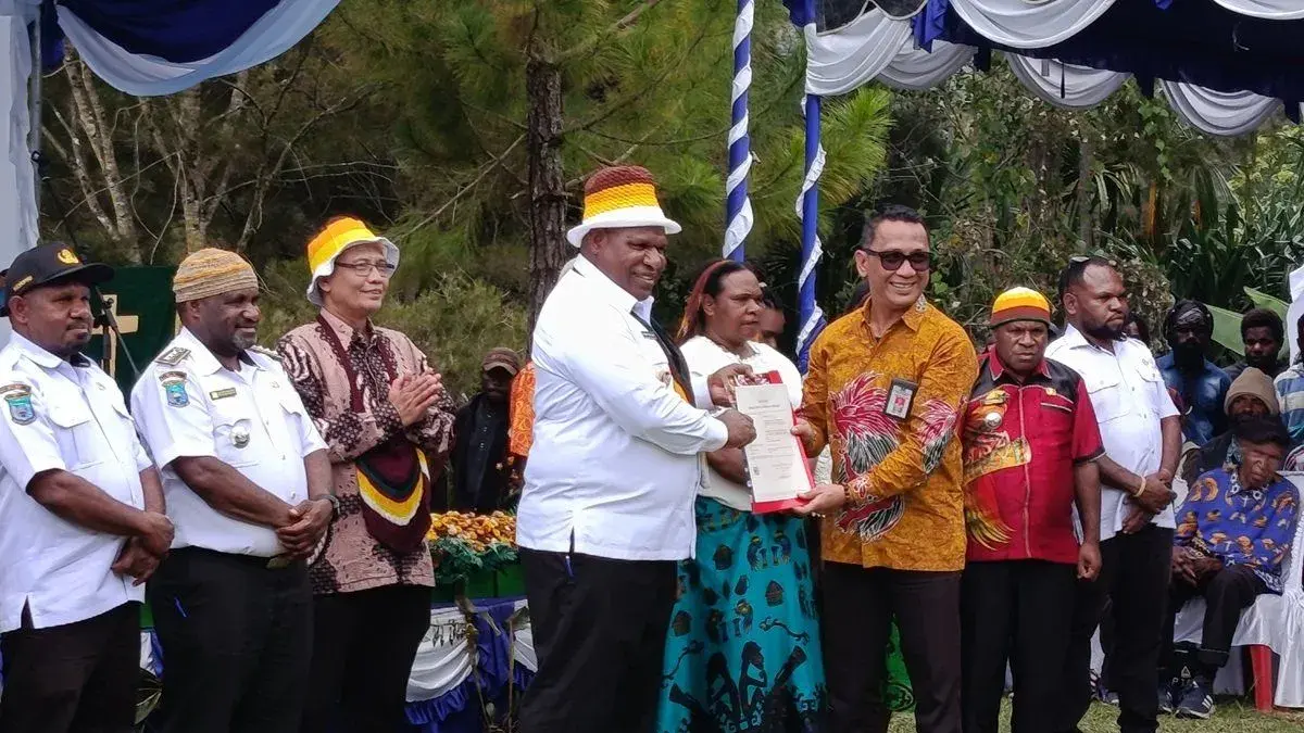 Analis Kekayaan Intelektual Kanwil Kemenkum Papua Rionard Simanjuntak (Batik kuning) menyerahkan surat pencatatan ciptaan Noken Cenderawasih kepada Bupati Jayawijaya Atenius Murib di Kampung Taganek, Distrik Yalengga, Kabupaten Jayawijaya, Rabu (24/6) 2026. (Antara/Yudhi Efendi)