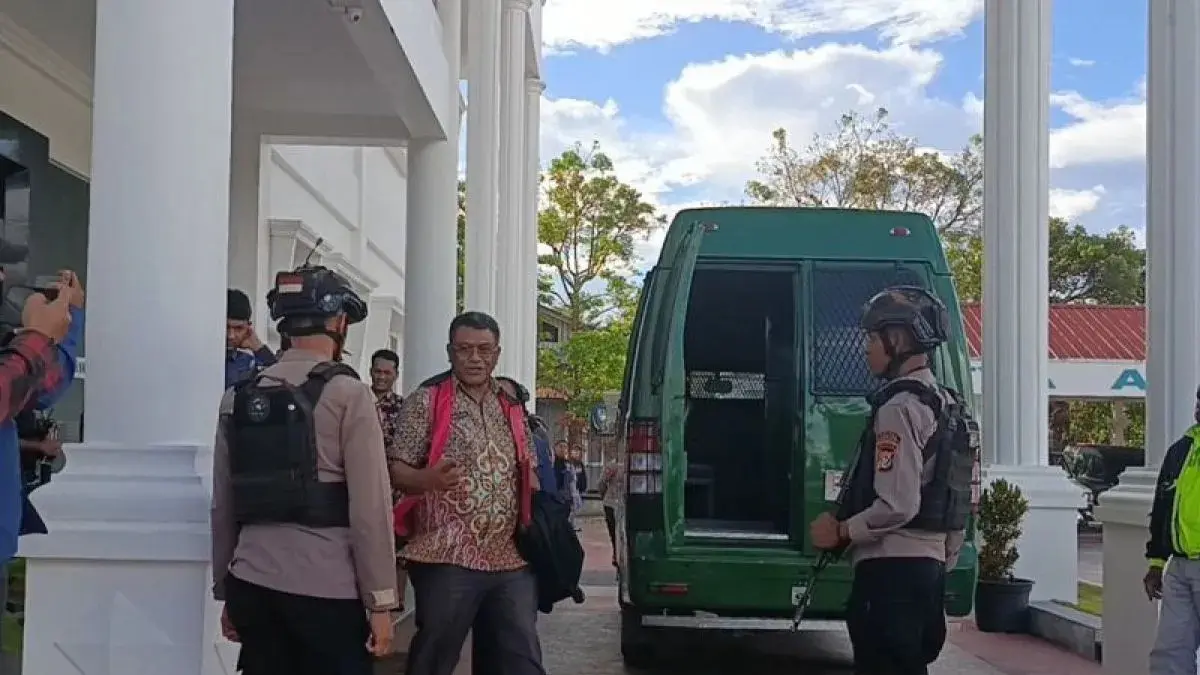 Tersangka TMM tanpa menggunakan masker dengan memakai rompi merah muda dikawal ketat aparat keamanan keluar dari Kejari Jayawijaya untuk naik ke dalam mobil tahanan dan dibawa ke Mapolres Jayawijaya untuk dilakukan penahanan, Kamis (2/7/2026). (ANTARA/Yudhi Efendi)

