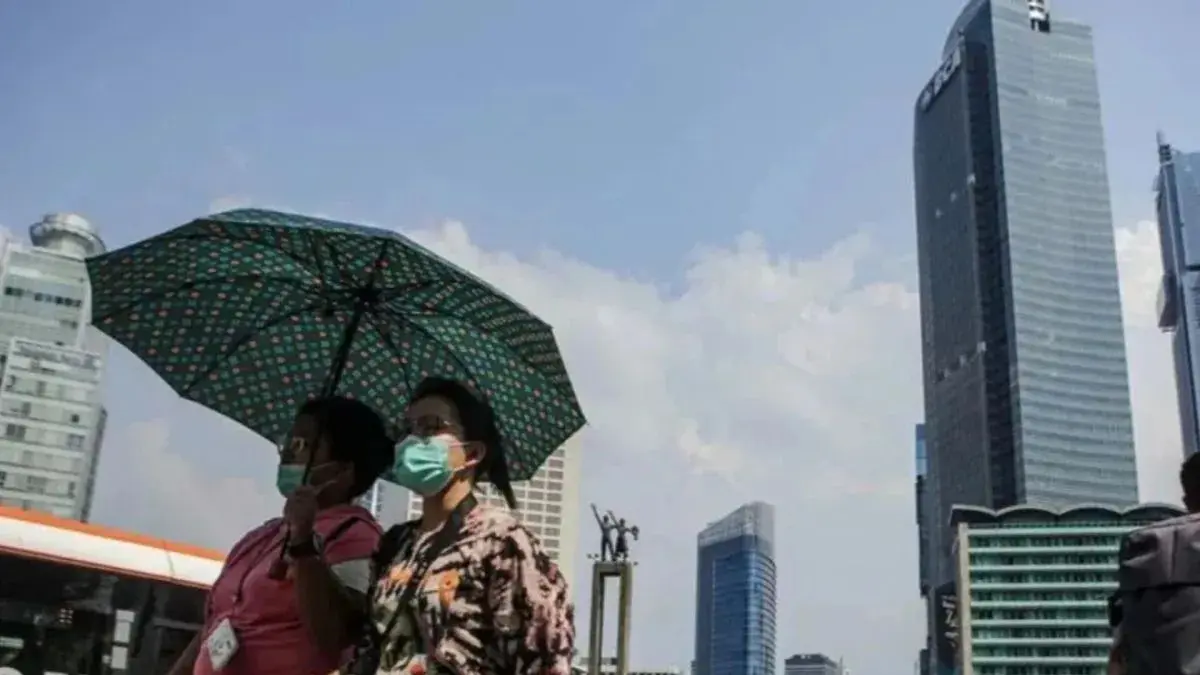 Warga berpayungan saat cuaca panas terik meliputi Jakarta. (ANTARA FOTO/Fauzan)