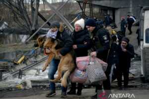 Seorang pria menggendong anjingnya saat warga menyelamatkan diri dari invasi Rusia di Ukraina, di Romanivka, Ukraina, Rabu (9/3/2022). REUTERS/Maksim Levin/FOC/djo (REUTERS/MAKSIM LEVIN)