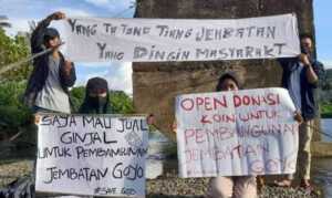 Warga memegang flyer jual ginjal untuk pembangunan Jembatan Goyo, Bolmut.