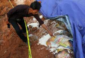 Garis polisi terpasang di area temuan karungan beras di tanah lapang Kampung Serab, Sukmajaya, Depok, Minggu (31/7/2022). Perusahaan pengiriman barang atau jasa ekspedisi diduga mengubur dan membuang puluhan karung beras untuk masyarakat terkena dampak CO