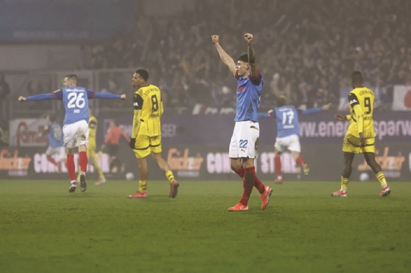 AFP/AXEL HEIMKEN RAYAKAN KEMENANGAN: Pemain Holstein Kiel, Nicolai Remberg (tengah), merayakan kemenangan setelah mencetak gol dalam kemenangan timnya 4-2 atas Borussia Dortmund dalam laga yang berla