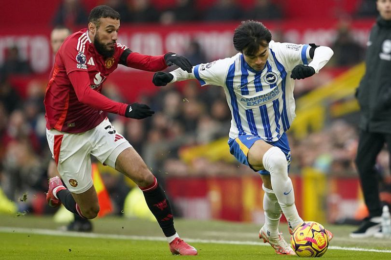AP Photo/Dave Thompson TETAPKAN HARGA JUAL: Bek Manchester United, Noussair Mazraoui beradu kecepatan melawan gelandang Brighton, Kaoru Mitoma.