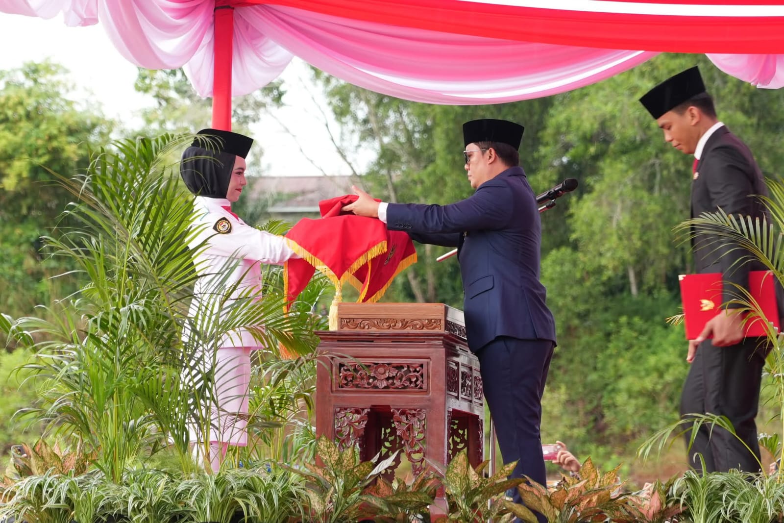 JADI IRUP: Bupati Tana Tidung Ibrahim Ali menyerahkan duplikat bendera pusaka kepada pengibar bendera di upacara HUT Ke 80 RI di lapangan RTH. H. Joeosoef Tideng Pale, Minggu 17/8/2025