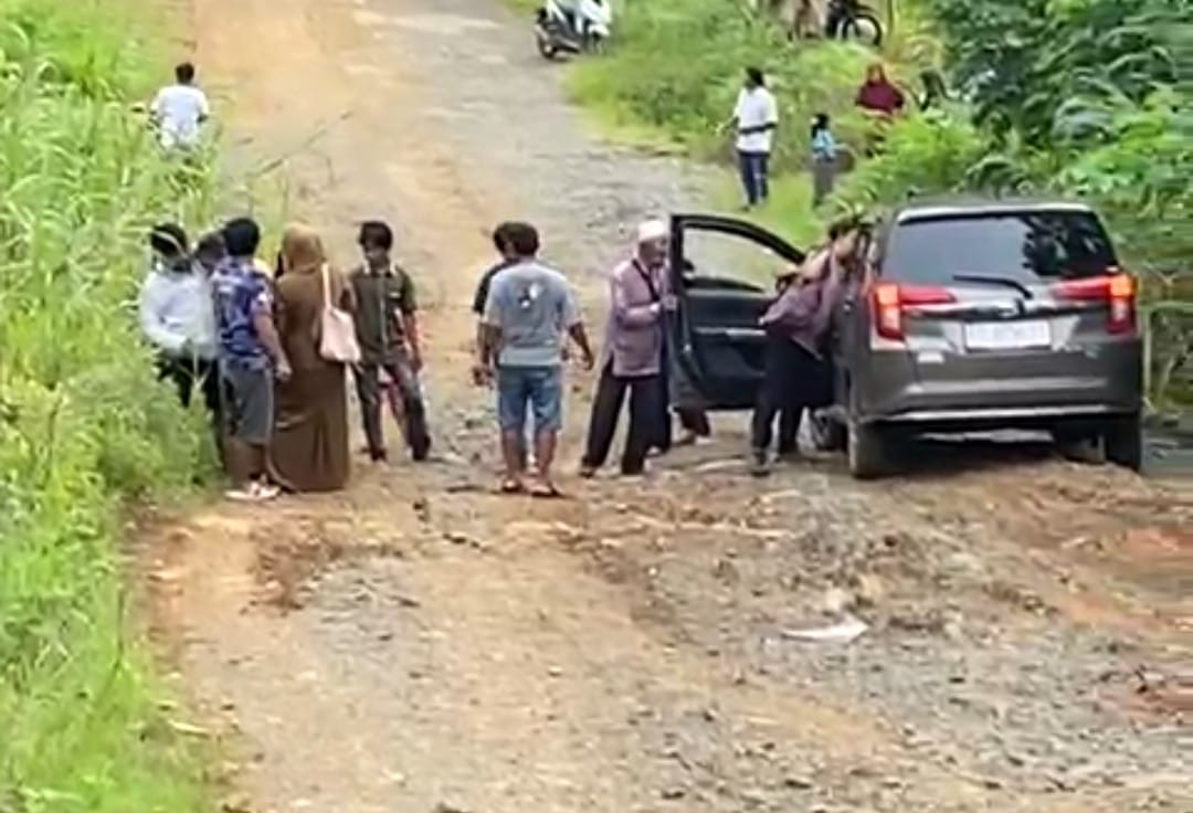 JALAN RUSAK : Warga mengevakuasi korban yang terjatuh di akses jalan menuju Puskesmas Sembakung