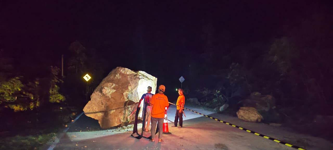 LONGSOR: Material batu berukuran besar menutup sebagian badan jalan.