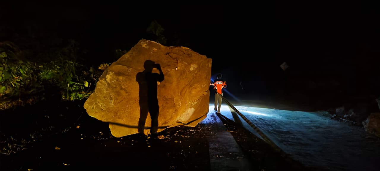 LONGSOR: Material batu berukuran besar menutup sebagian badan jalan.