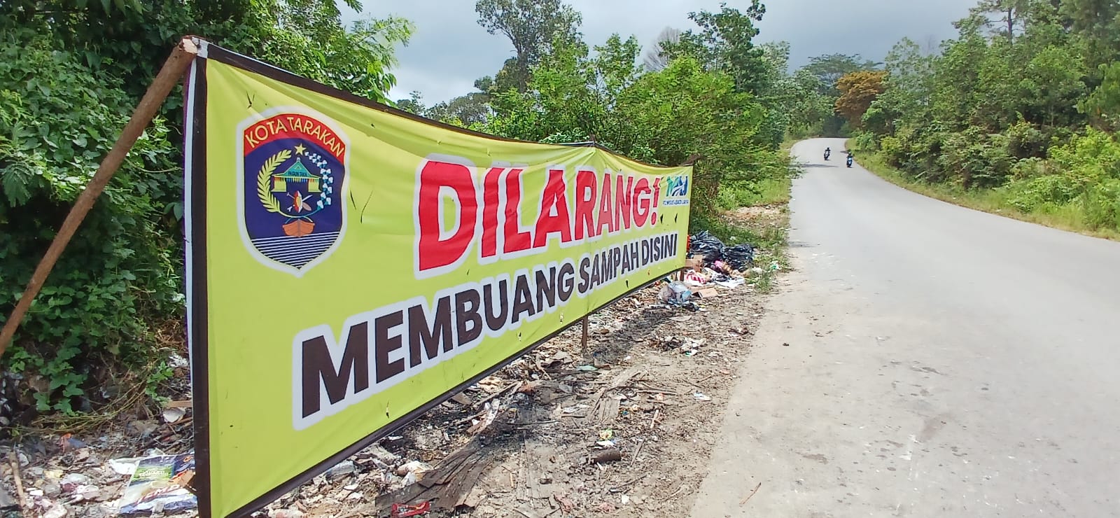 BERSAMPAH : Kondisi jalan Gunung Selatan masih menjadi lokasi pembuangan sampah meski terpasang banner peringatan.  