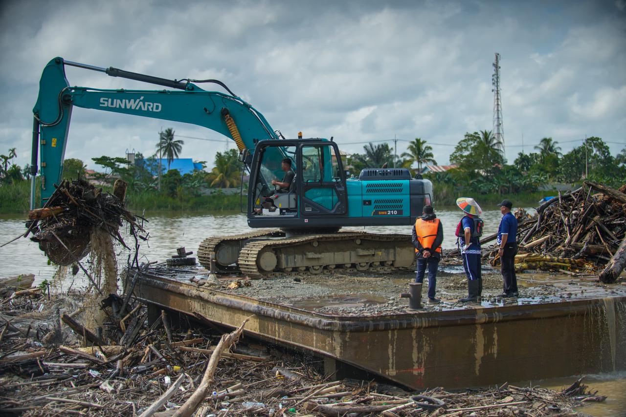 AKSI: Proses pembersihan batang kayu dan sampah yang terseret banjir dan tertahan di jembatan Malinau.