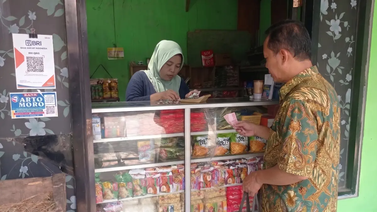 TRANSAKSI UMKM – Seorang pelanggan melakukan pembayaran di warung kelontong yang telah menggunakan layanan QRIS BRI. Kehadiran sistem pembayaran digital tersebut membantu pelaku UMKM menerima transaksi non-tunai dengan lebih mudah, cepat, dan aman. Foto: BRI.