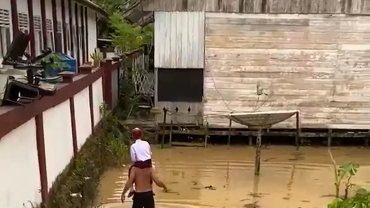 PERJUANGAN : Demi buah hatinya mengikuti MPLS, orang tua menggendong anaknya melewati banjir untuk sampai ke sekolah.&nbsp;