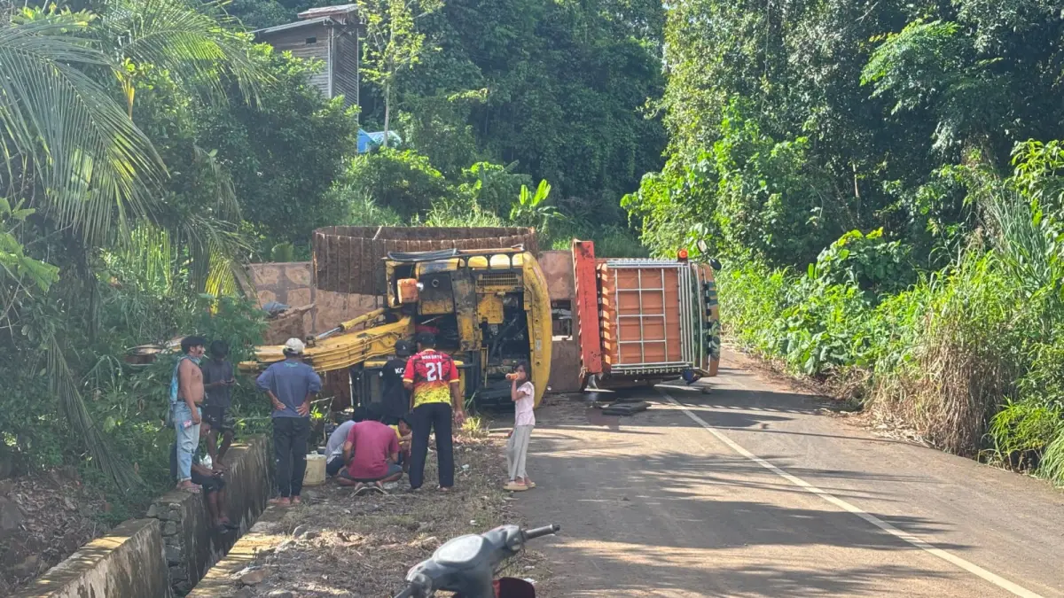 TERBALIK : Truk pengangkut ekskavator terbalik dan menutupi ruas jalan antara kecamatan.&nbsp;