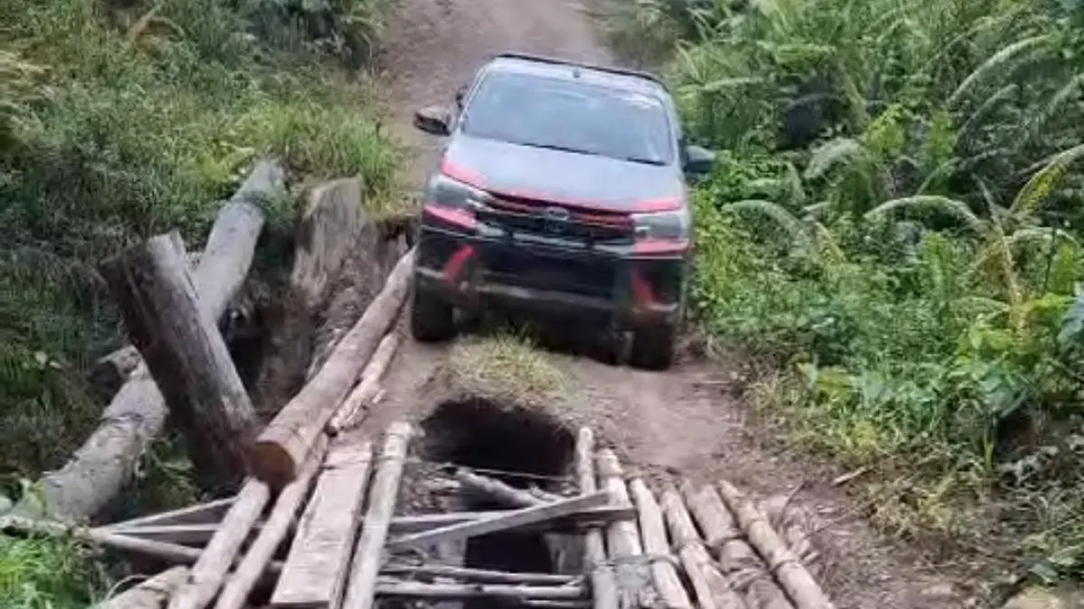AKSES JALAN: Sebuah kendaraan melintas dengan hati-hati di jembatan kayu yang mengalami kerusakan parah di salah satu wilayah di Kaltara. FOTO: DOK WARGA