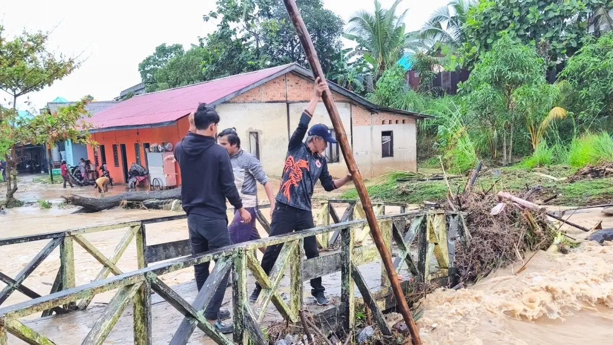 PENANGANAN: Personel BPBD Nunukan saat melakukan pembersihan material banjir yang tersangkut di jembatan.&nbsp;