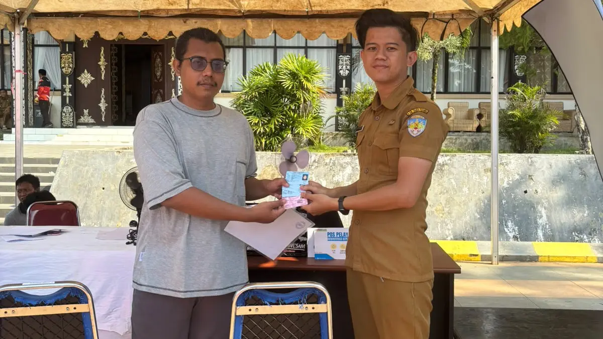 CETAK ADMINDUK: Salah seorang korban kebakaran menerima dokumen Adminduk berupa KTP-el dan KIA. 