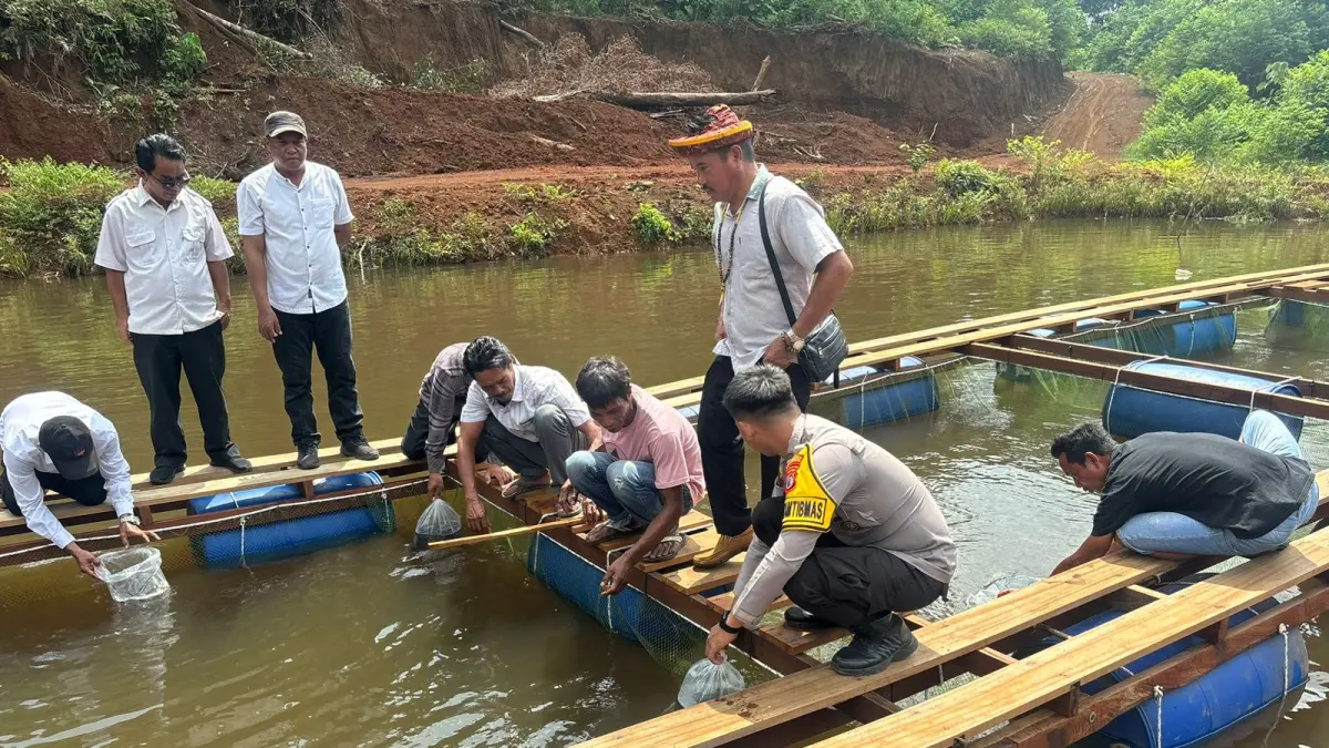 KETAHANAN PANGAN: Bhabinkamtibmas bersama masyarakat menabur ribuan benih ikan nila dan emas di kolan warga Desa Sebidai. (FOTO: IST)