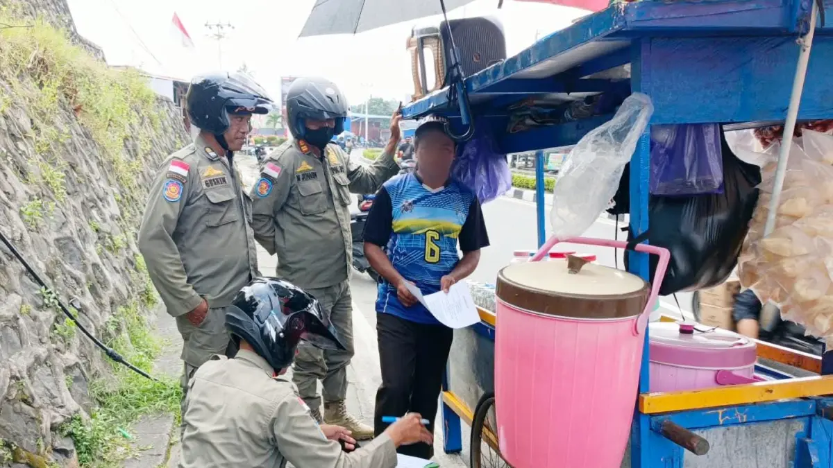 EDUKASI : Personel Satpol PP melakukan imbauan kepada PKL yang beraktivitas menggunakan badan jalan.&nbsp;