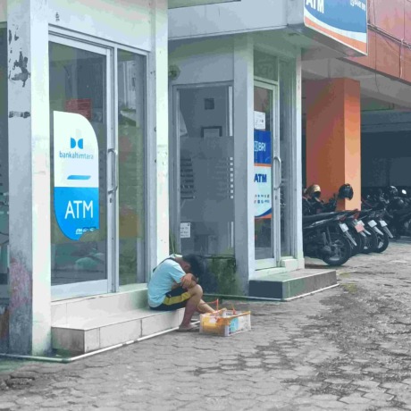BERJUALAN: Seorang anak usia sekolah sedang berjualan di depan mesin ATM di Kantor Gadis Pemkot Tarakan, Jumat (30/12). FOTO: AGUS DIAN ZAKARIA/RADAR TARAKAN