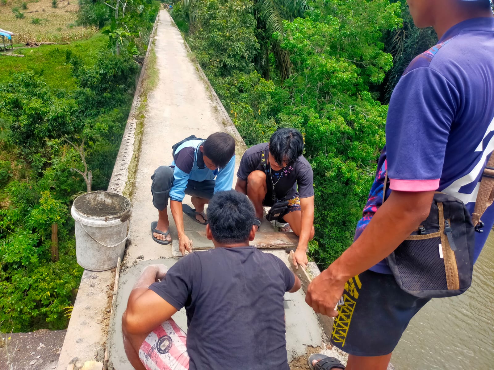 Muda-mudi Nagori Bayu Bagasan, Tanah Jawa, Kabupaten Simalungun, bekerjasama memperbaiki jembatan yang berlubang-lubang secara swadaya.