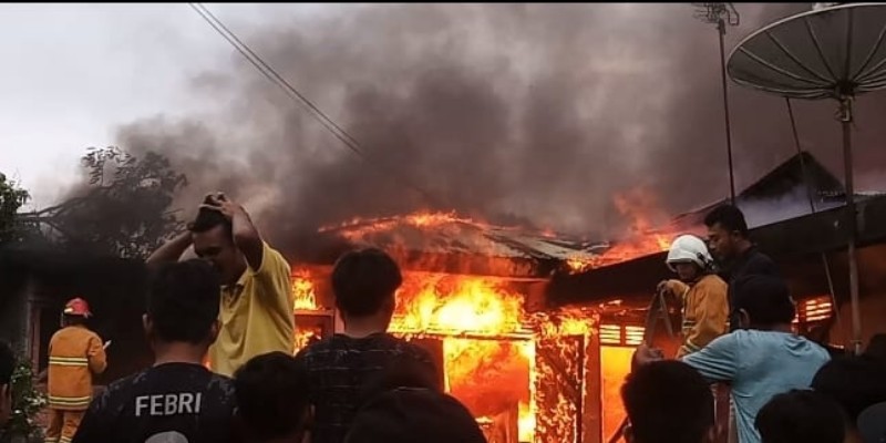 Petugas pemadam kebakaran saat berupaya memadamkan api yang membakar rumah semi permanen milik Dewi Purba.