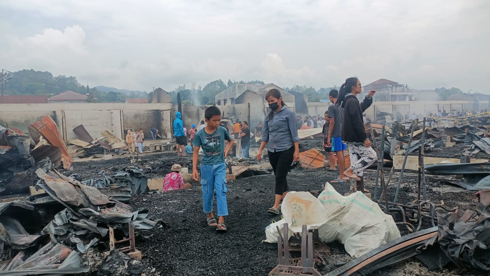 Pemilik kios berada di tengah puing-puing kebakaran  dan masih terlihat asap menyusul peristiwa kebakaran Pasar Tarutung yang terjadi Minggu (7/4/2024).