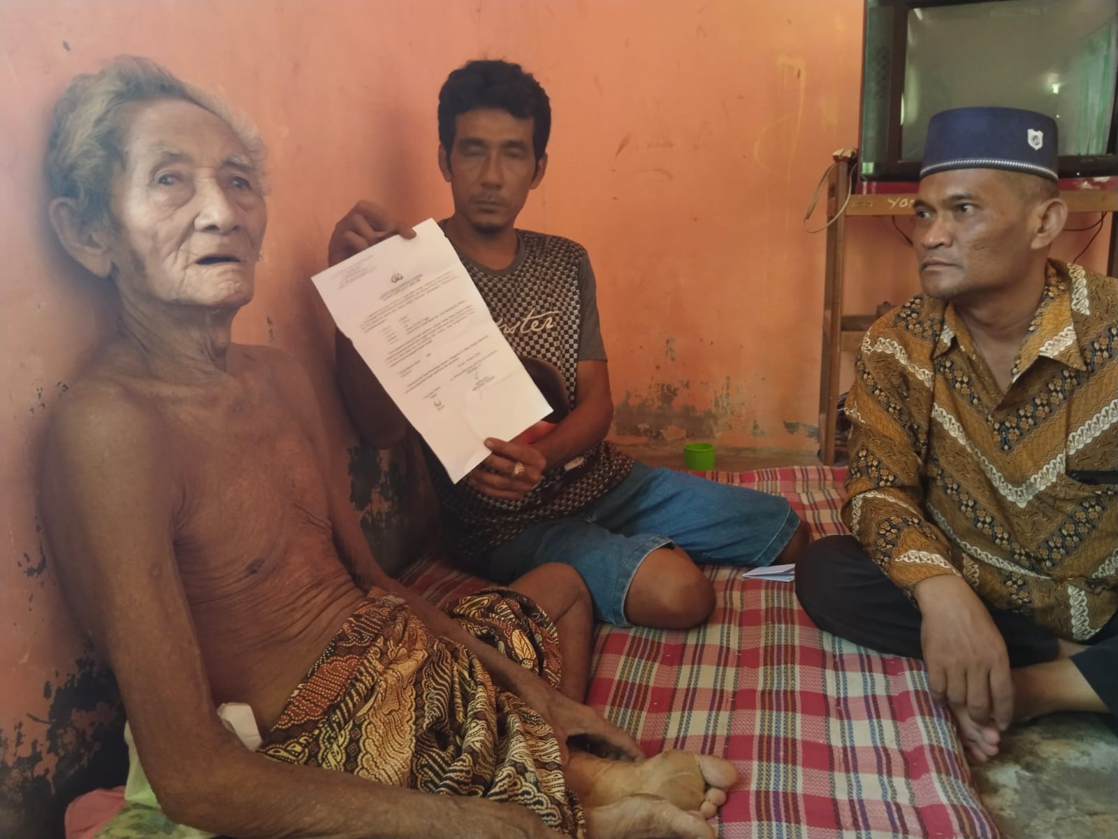 Korban (kiri) saat ditemui di rumahnya sementara anak lelakinya menunjukkan surat laporan Polisi beberapa waktu lalu.