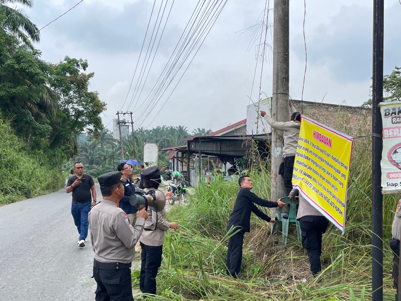 Petugas Kepolisian saat memasang spanduk himbauan Kamtibmas di jalan Perlayuan, Labuhanbatu.