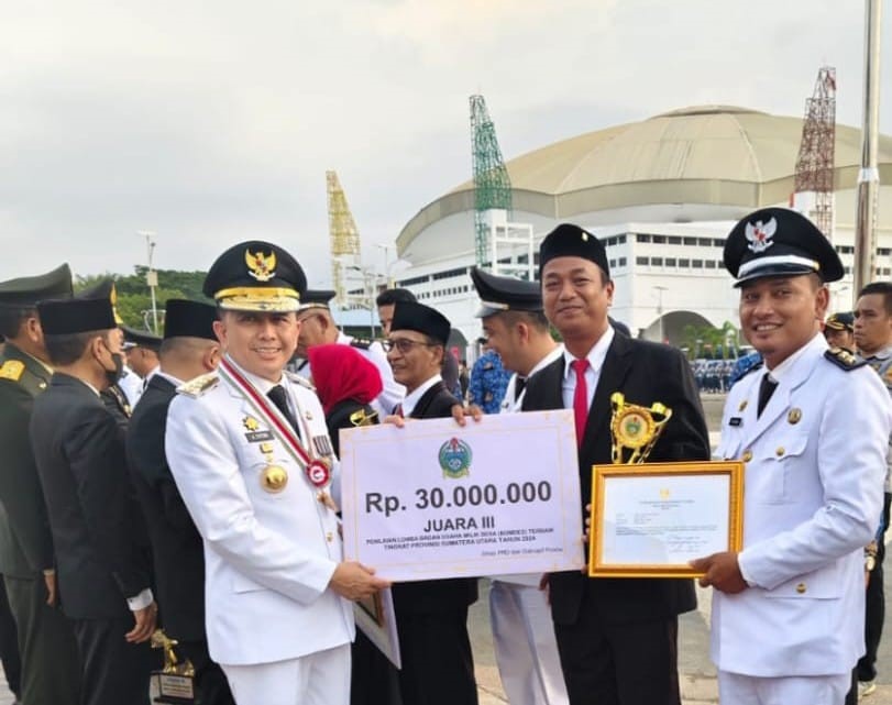Pj Gubernur Sumut Agus Fatoni menyerahkan trofi dan hadiah kepada Pangulu Nagori Bosar Bayu Edu Sitorus bersama pengurus BUMNag Tama Ture.