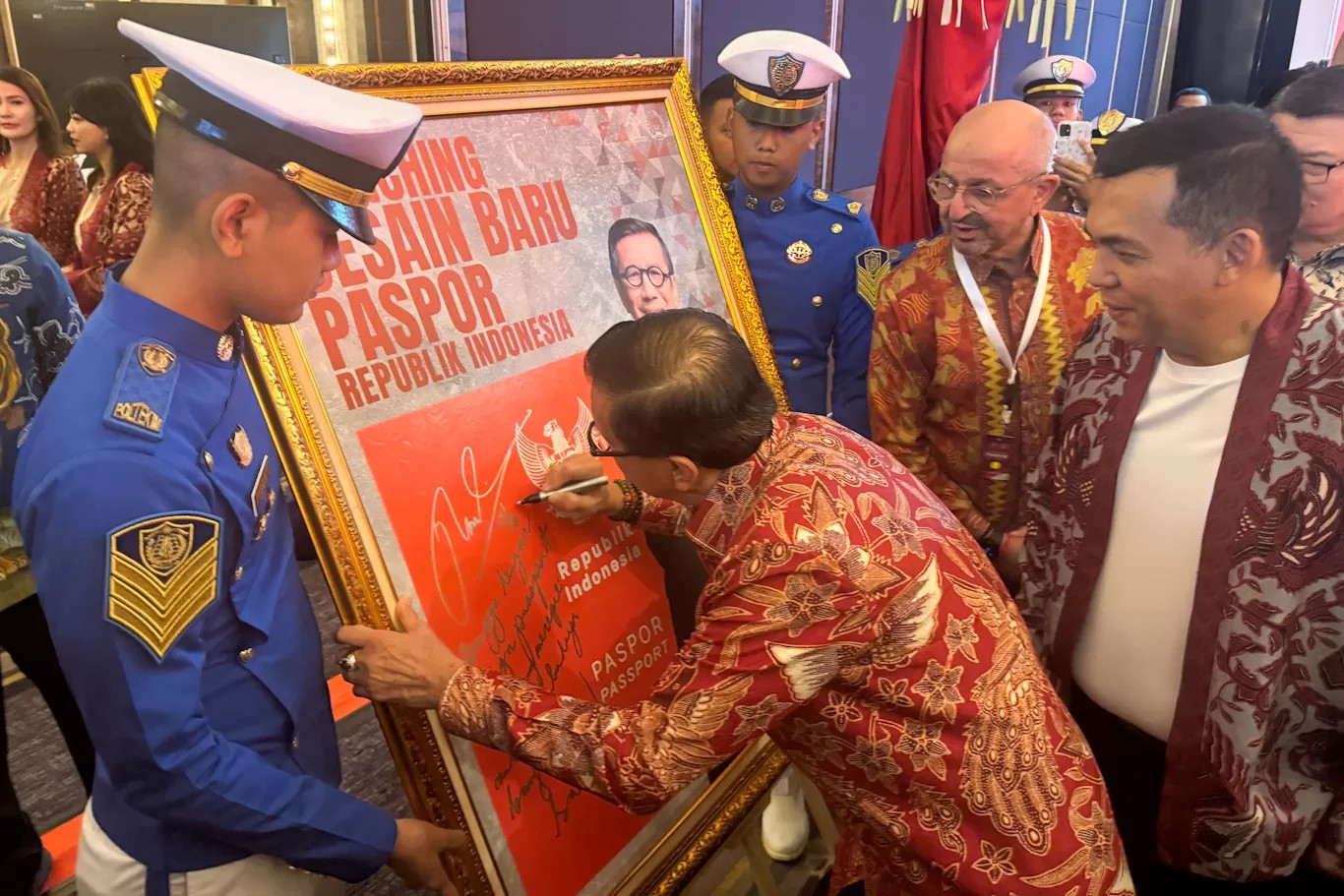 Menkumham Yasonna Laoly menandatangani poster peluncuran desain baru paspor Indonesia yang kini berwarna merah.
