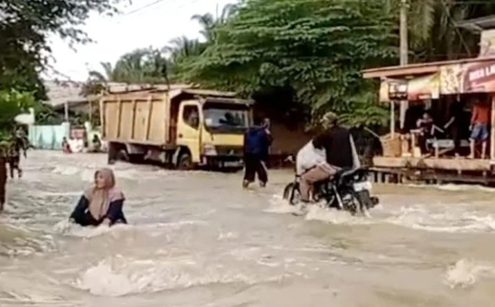 Warga pengendara sepeda motor berusaha menerobos banjir yang mengalir deras di jalan provinsi, Desa Sennah, Kecamatan Pangkatan, Kabupaten Labuhanbatu, Selasa (15/10/2024).