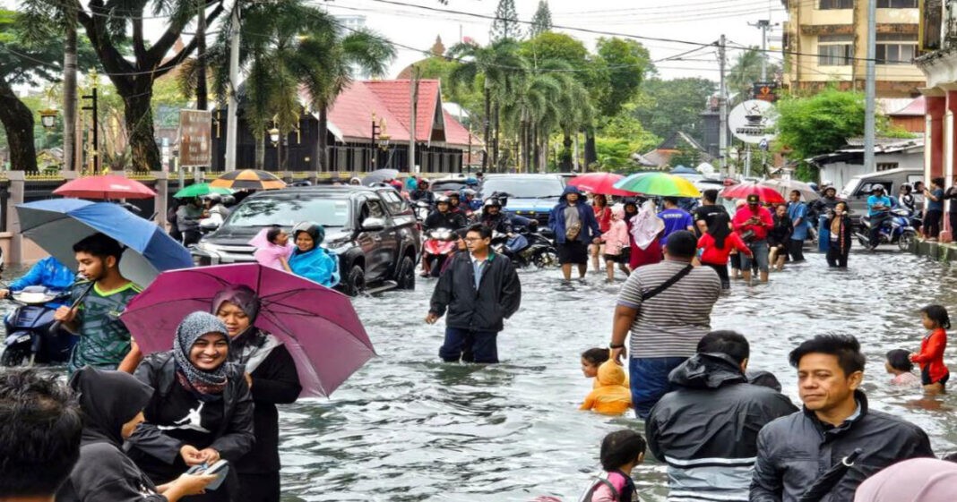Warga berjalan di jalanan yang tergenang air setelah hujan deras di pusat Kota Bharu, Kelantan, Malaysia, pada 29 November 2024.