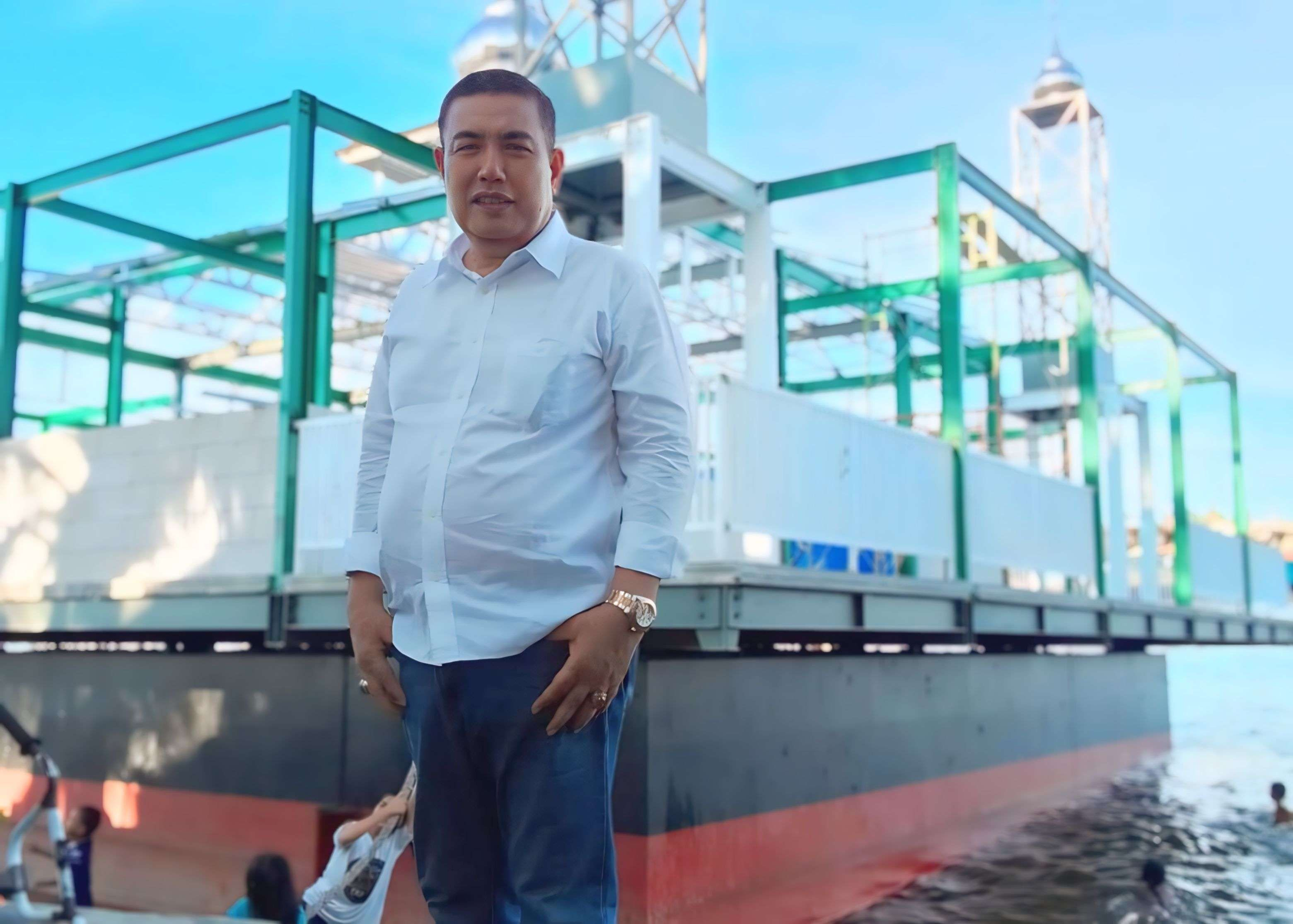 Zaharuddin Sinaga dengan latar belakang mesjid terapung yang masih dalam proses pembangunan.