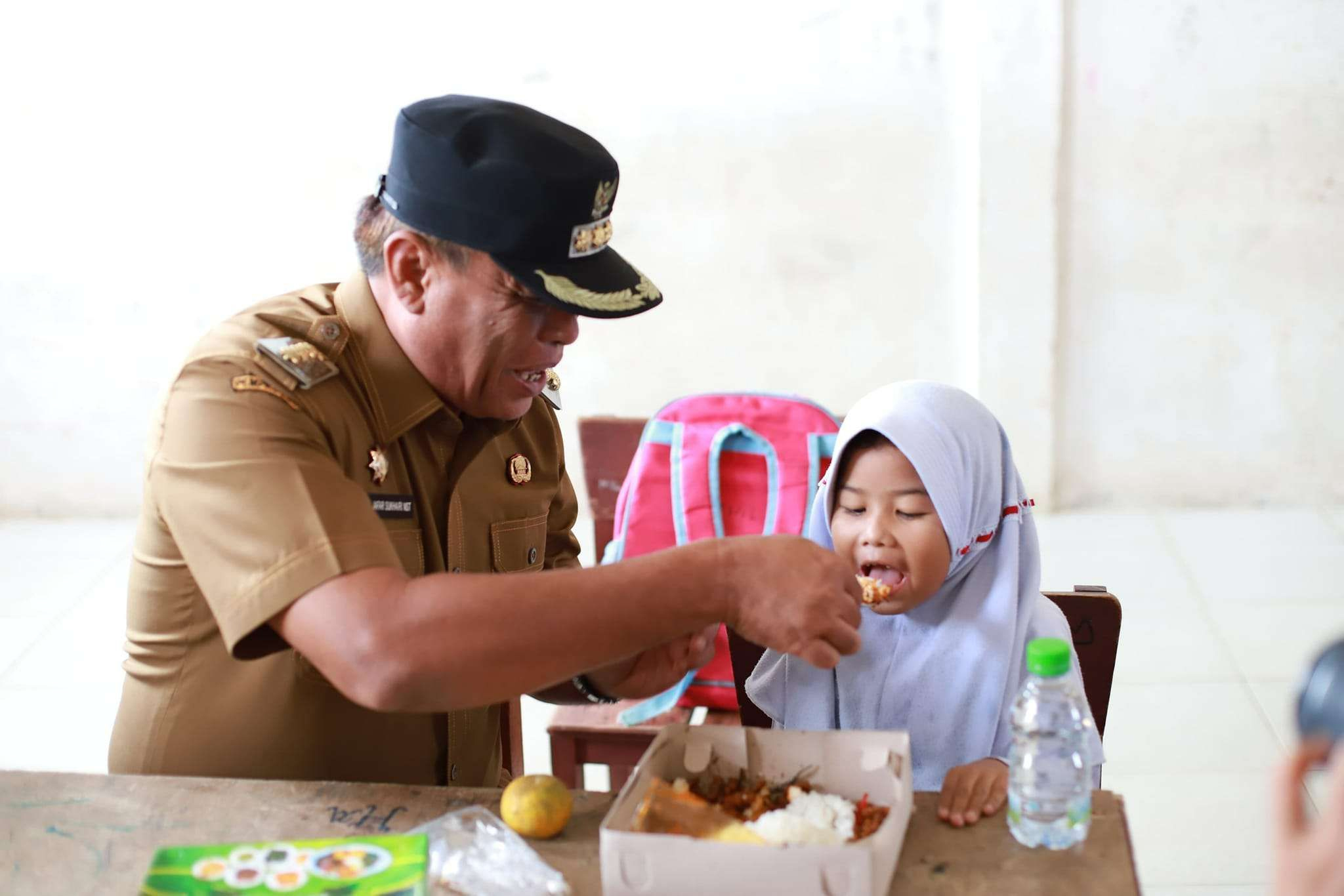 Bupati Madina saat memberikan Makanan Bergizi terhadap seorang siswi SD.