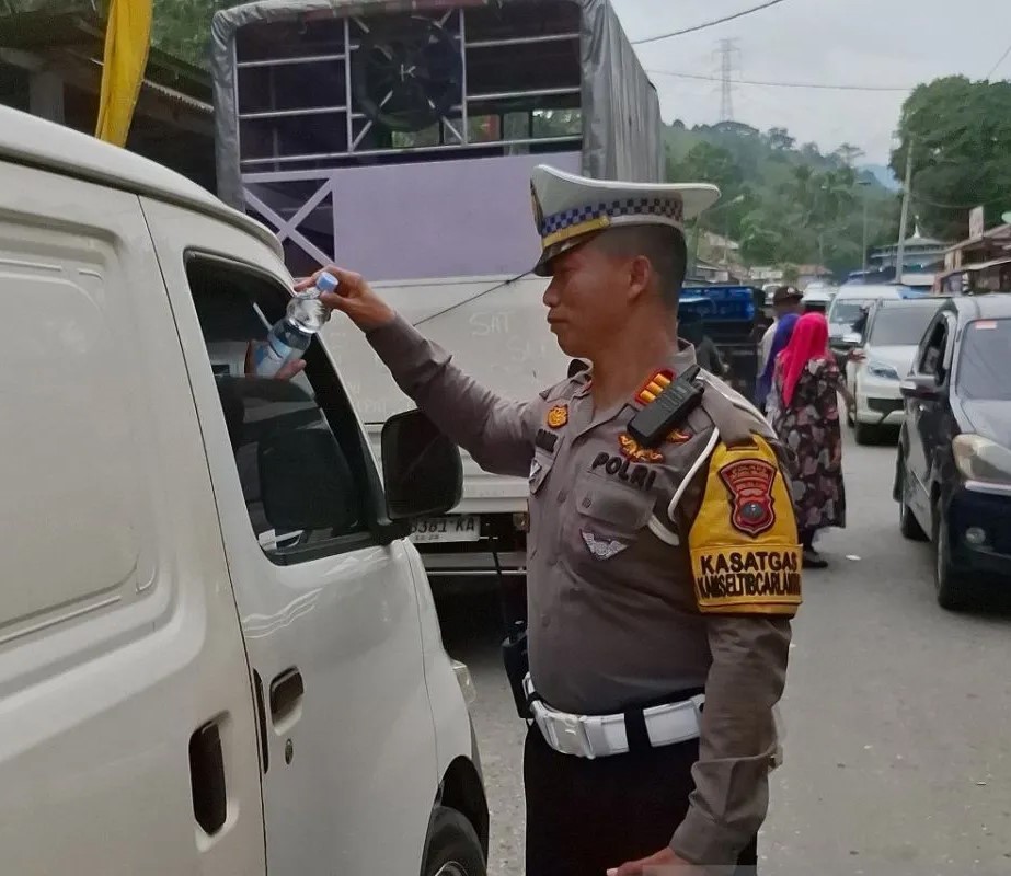 Personel Polres Tapsel membagikan air mineral kepada pengendara di Pos Pengamanan Aek Sijorni.