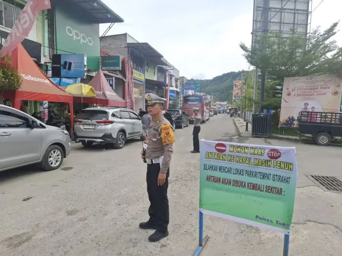 Personel Polres Toba berusaha mengurai kemacetan dengan mengatur arus lalu lintas di daerah Pelabuhan Ajibata.