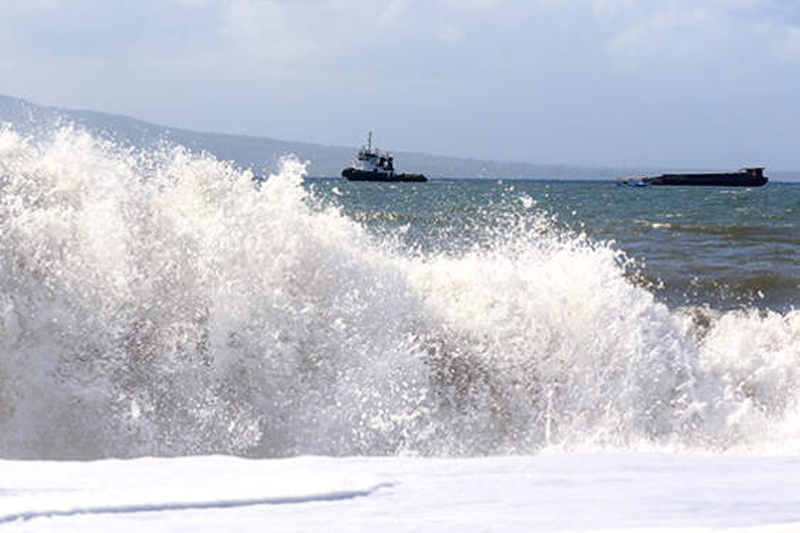 Kapal tongkang berlayar saat gelombang tinggi di Selat Bali terlihat dari Pantai Boom, Banyuwangi, Jawa Timur, Sabtu (1/6/2019). Badan Meteorologi Klimatologi dan Geofisika (BMKG) Maritim mengeluarkan peringatan dini gelombang tinggi sekitar 1.25 - 2.50 m