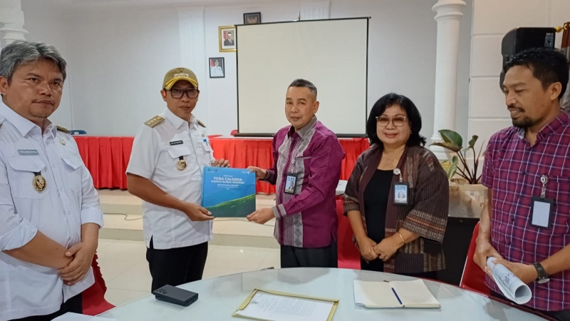 General Manager Badan Pengelola TC-UNESCO Global Geopark, Azizul Kholis menyerahkan buku Toba Caldera yang memaparkan keanekaragaman geologi, biologi, dan budaya, kepada Bupati Tapanuli Utara, Jonius.