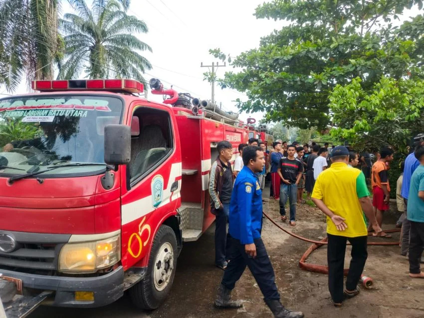 Petugas kebakaran Pemkab Labura dan masyarakat memadamkan api.