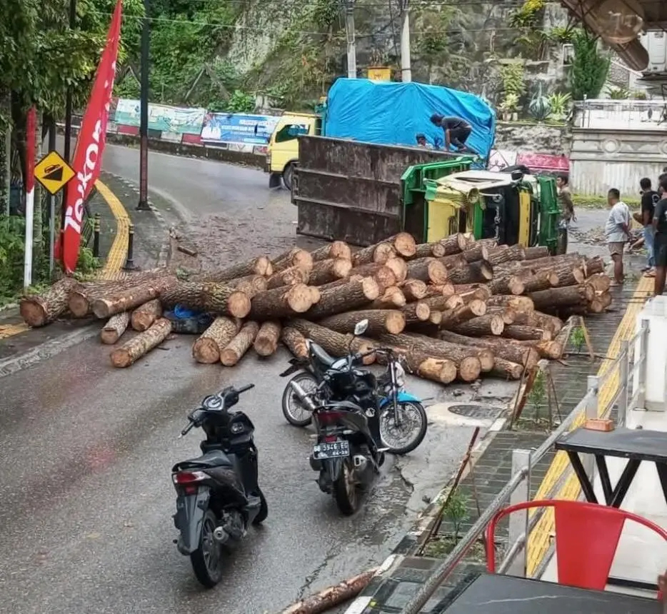 Sebuah truk bermuatan kayu pinus terbalik di Simpang Ajibata, Kabupaten Toba, Sumatera Utara, Minggu (23/3/2025) sore.