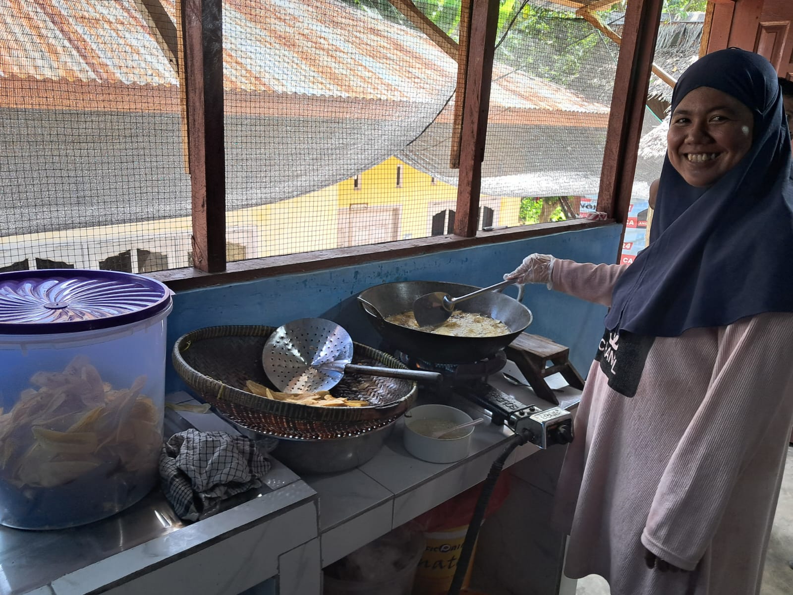 Dewi Juliani Sembiring  pengusaha UMKM keripik pisang dengan brand Bunda 2R, sedang menggoreng keripik di dapur produksinya bantuan dari PTAR.