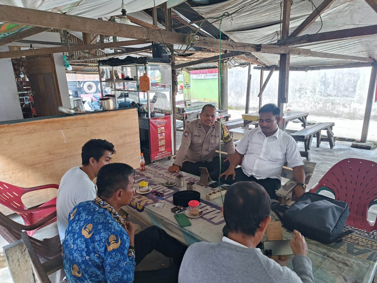 Bhabinkamtibmas Kelurahan Pantai Johor, Aipda Arifin Siregar saat melaksanakan kegiatan sambang dialogis ke warung kopi Nasution.